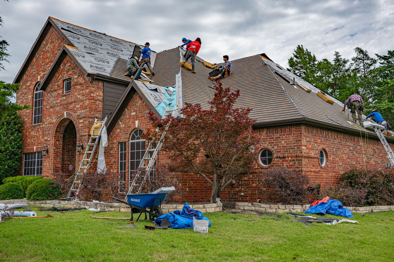 Workers renovating roof of brick house in texas