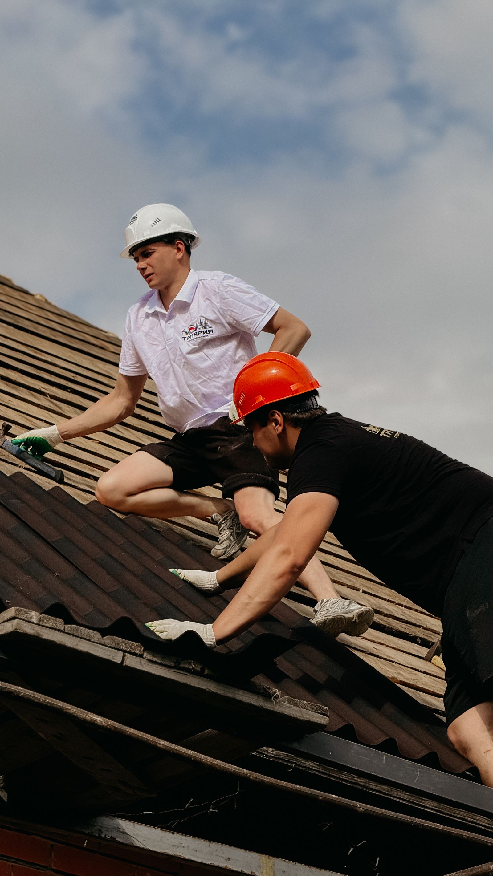 Construction workers repairing roof with safety gear