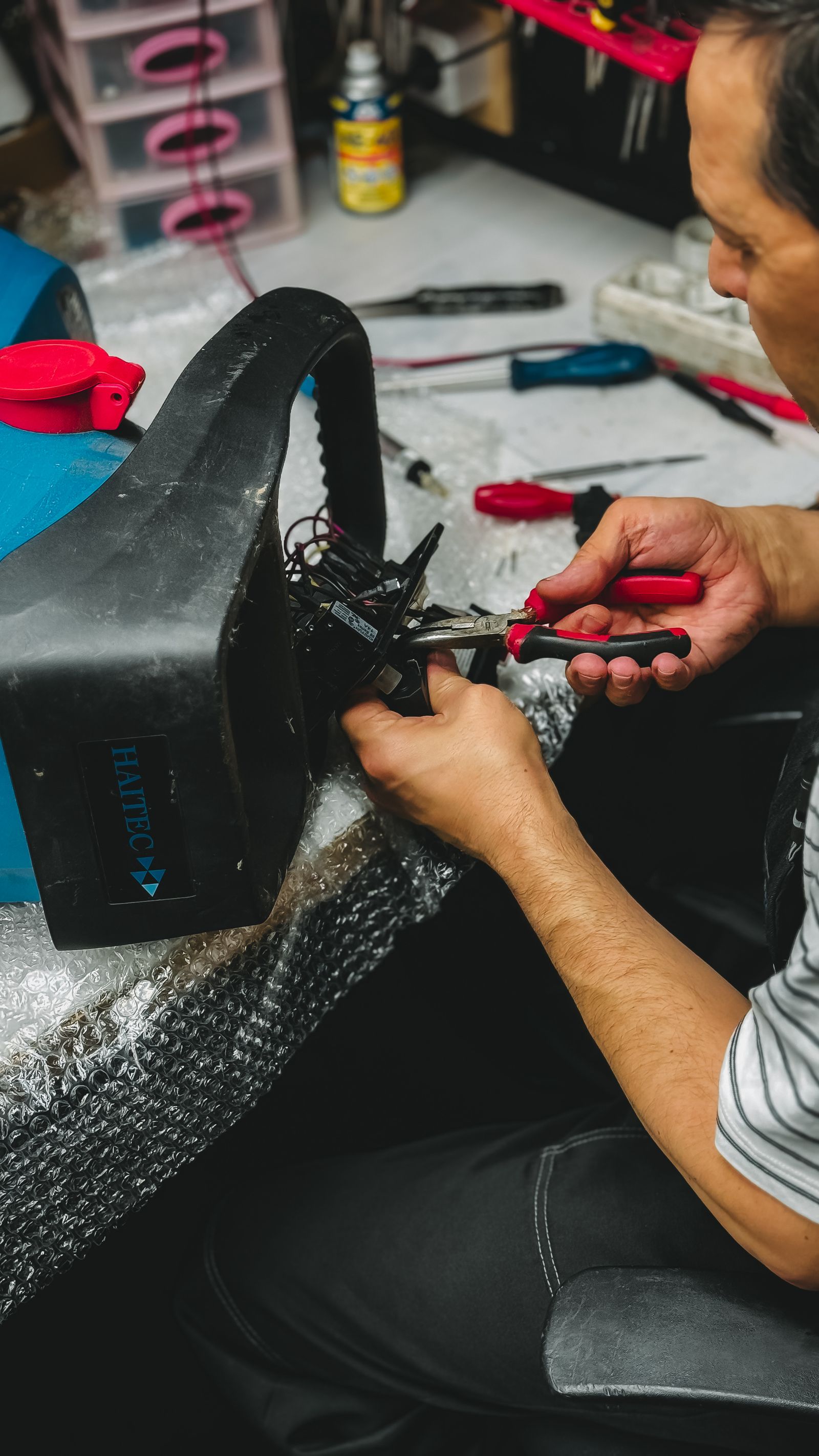 Man repairs drone using pliers in workshop