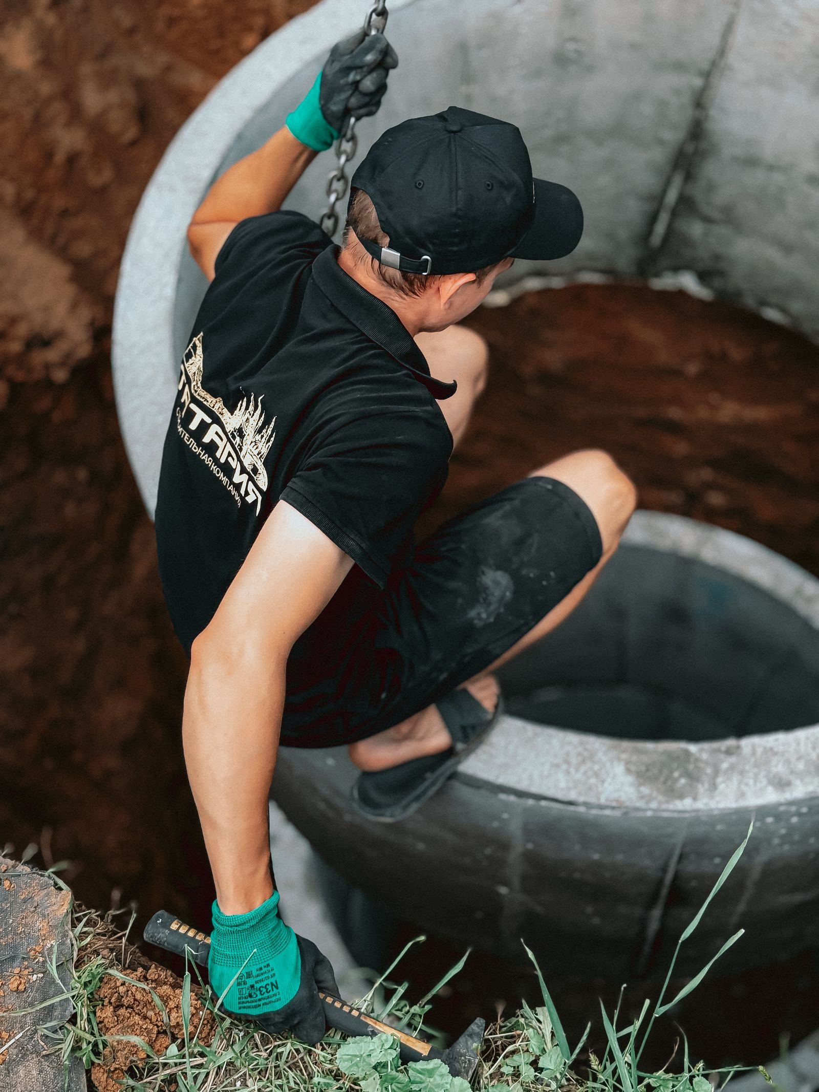 Construction worker installing a concrete well segment outdoors