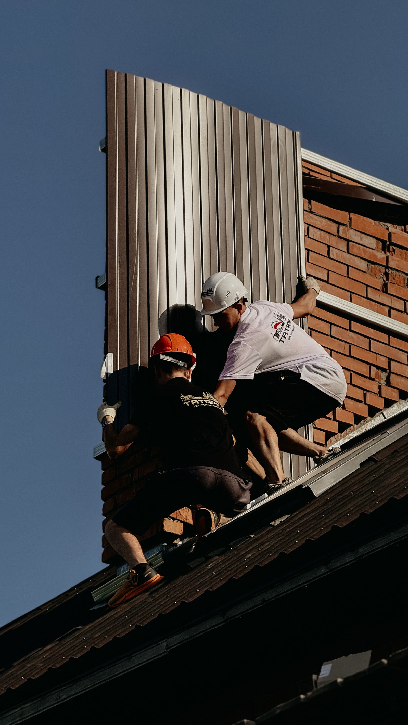Construction workers installing roof panels