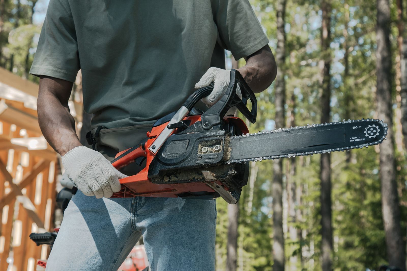 An adult holding a chainsaw outdoors, showcasing forest work equipment usage