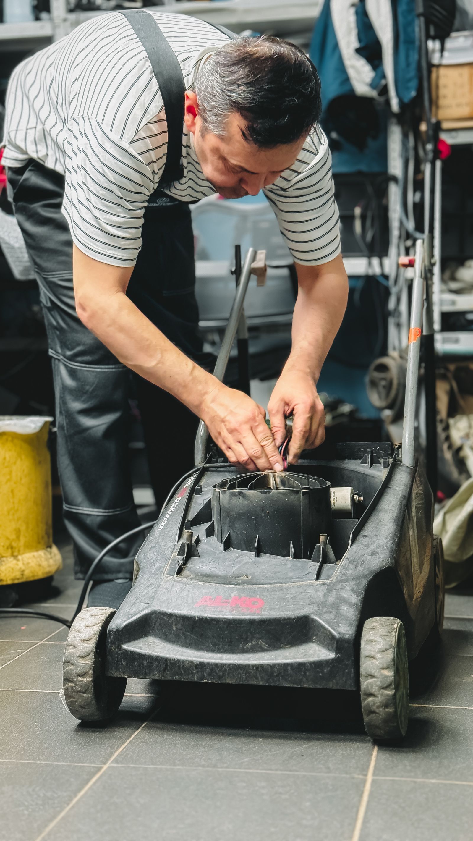 Man repairing lawn mower in garage workshop