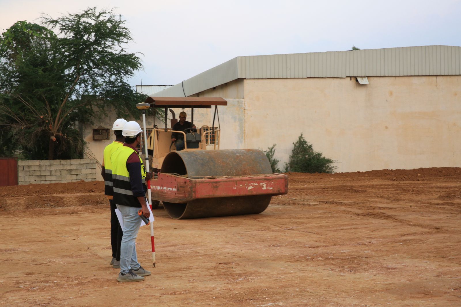 Construction workers operating road roller at site