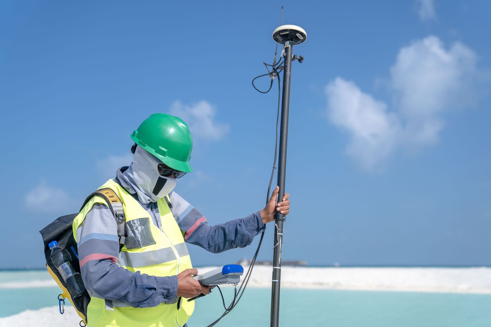 Man in helmet goggles and mask standing with device