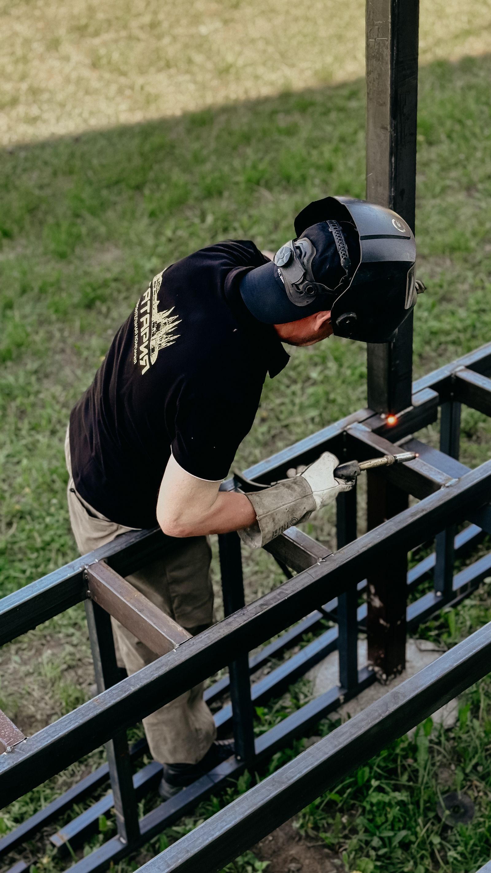 Welder working on metal frame outdoors
